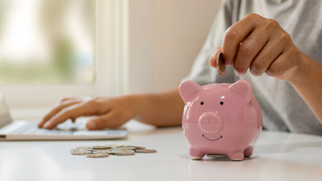 Women put money coins into piglets to save money and save money for future investment financial and investment ideas.