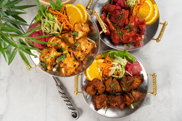 Chicken, beef, and pork shashlik with vegetable garnish and spicy spices, cooked in tandoor. A set of three hot meat dishes in traditional Indian plates. Kebab fried on a skewer.