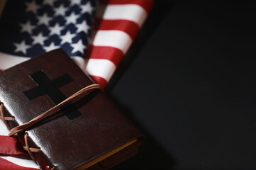 Fototapeta na wymiar American flag and holy bible book on a mirror background. Symbol of the United States and religion. Bible and striped flag on a black background.