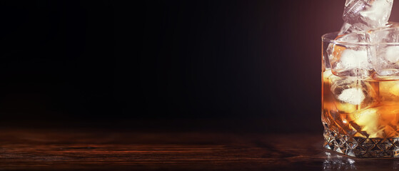 A glass of strong alcoholic drink with ice on a wooden bar counter. Whiskey with ice cubes. Glass with a chilled drink.
