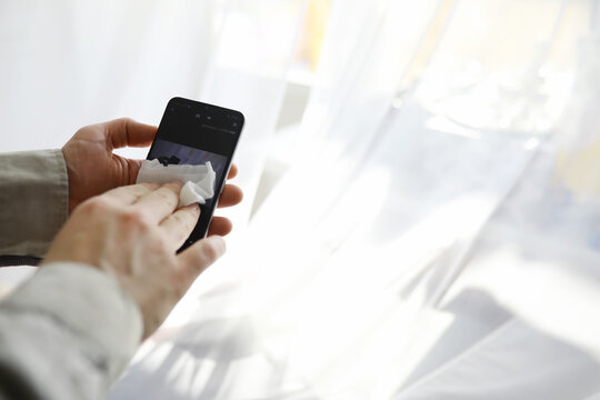 Сleaning concept. Wipe dirt off surfaces. Disinfectant treatment of phone screenl. Sanitary treatment at home quarantine.