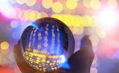 Crystal Ball on the floor with bokeh, lights behind. Glass ball with colorful bokeh light, celebration concept.