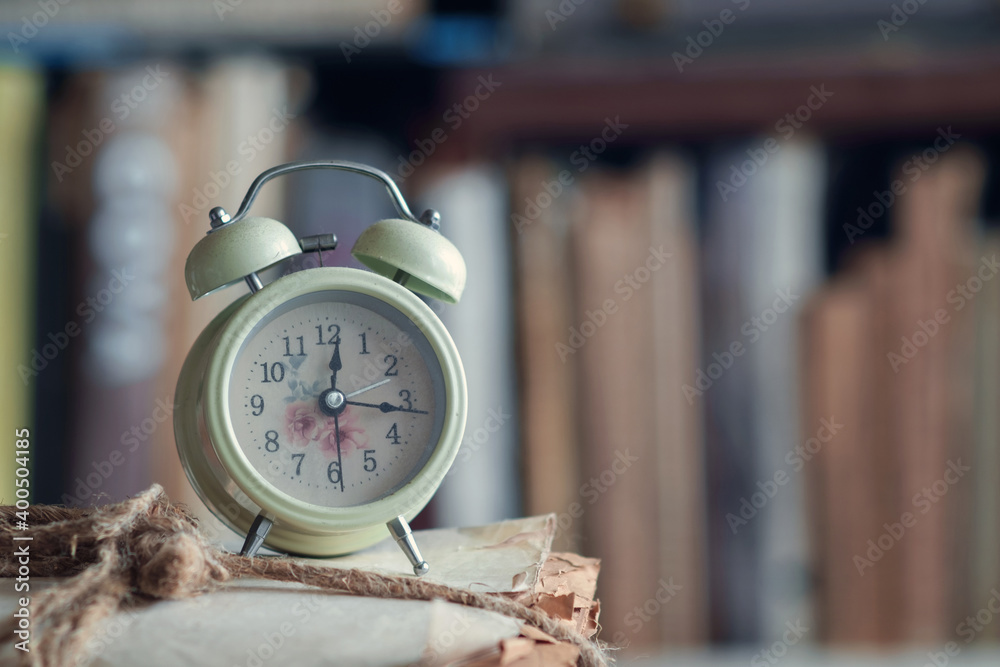 Wall mural vintage alarm clock on the pile of papers at library, selective focus