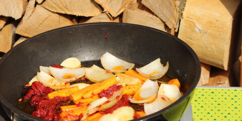 Onions and carrots are sautéed in a pan with tomato paste