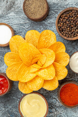 Vertical view of homemade potato chips decorated like flower shaped in a brown bowl on gray background