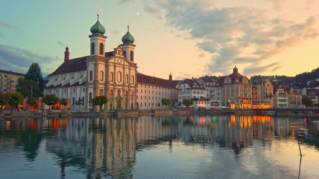 Amazing colorful sunset city center of Lucerne of Lake Lucerne in Central Switzerland. Jesuitenkirche or Jesuit Church of St. Francis Xavier reflects on Reuss river. Famous landmark of historical city