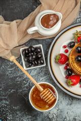 Obraz na płótnie Canvas top view delicious pancakes with fruits and honey on a light background sweet fruit cake