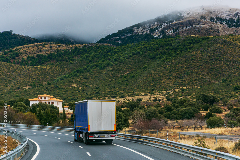 Canvas Prints truck driving on a highway with mountains with snow and fog in the background.