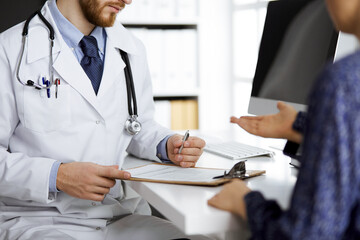 Fototapeta premium Female doctor and male patient discussing current health examination while sitting in clinic, close-up. Medicine concept