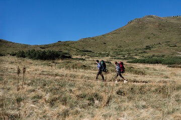 couple in love tourists man and woman stand walking along a mountain path, large backpacks. Hiking concept.