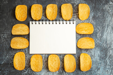 Top view of crunchy baked five chips laid and notebook among them on gray background stock photo