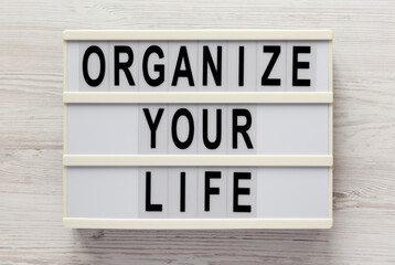 'Organize your life' on a lightbox on a white wooden background, top view. Flat lay, overhead, from above.