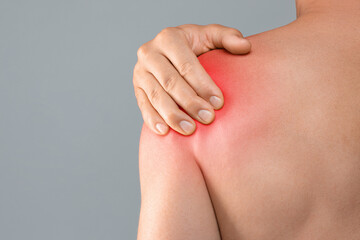 Closeup of topless man suffering from pain in shoulder