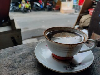 Black coffee cup on a wooden table in the street