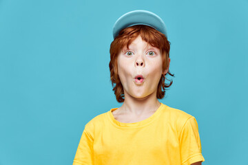 redhead boy surprised facial expression blue cap yellow t-shirt studio 