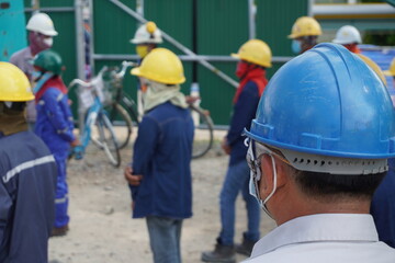 (Focus on the safety helmet) Construction worker in a safety meeting on morning talk before work at oil and Gas factory or Chemical plant under construction site.