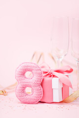 8 March, International Women's Day concept. Figure eight of pink crochet with luxury gift box, big bow on pink background. Space for text, monochrome seasonal holiday greeting card