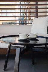 Defocused Two white coffee cups on a table with blurred balcony partition light background