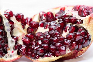 Broken juicy bright ripe pomegranate on a white background close