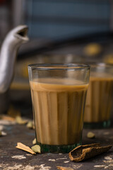 Indian chai in glass cups with metal kettle and other masalas to make the tea. 
