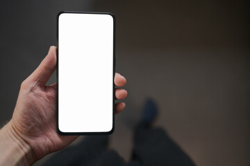Man hold smartphone with white screen in his hand standing indoors in home environment