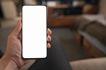 Man hold smartphone with white screen in his hand sitting on a couch in home environment