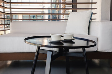 Two white cups of morning coffee for breakfast on a coffee table on a balcony.