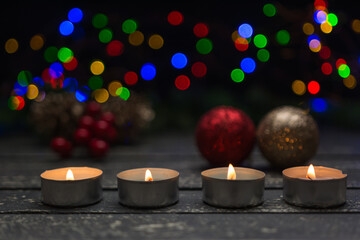 Lighted candles on a wooden base and scattered holiday decorations.