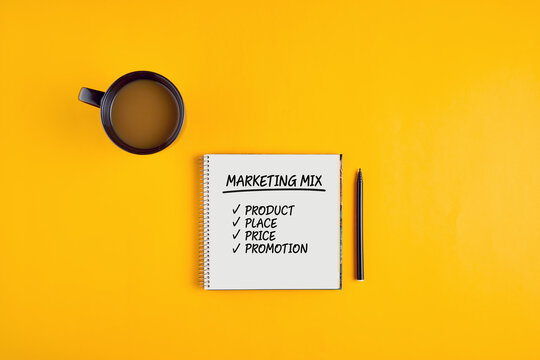 The word marketing mix written on notebook with pen and coffee mug