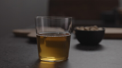 apple cider in glass and pistachios in black bowl on concrete countertop