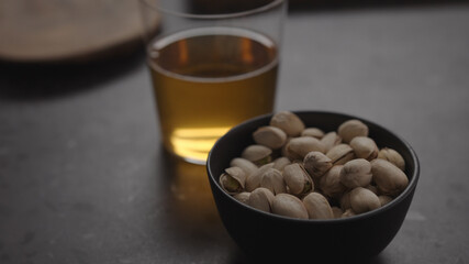 apple cider in glass and pistachios in black bowl on concrete countertop