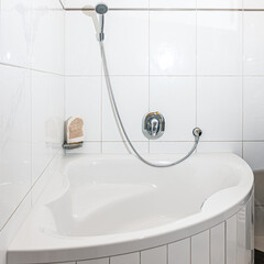Badezimmer mit Eckbadewanne, weiß gefliest