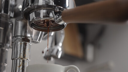 low angle shot of coffee extraction with naked portafilter into white cup