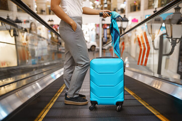 Young woman with suitcase on escalator in airport