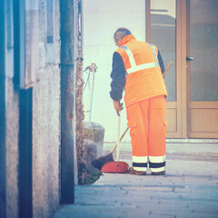 Obraz na płótnie Canvas Sweeper working on sidewalk. Square picture of cleaner worker with high-visibility jacket in the city