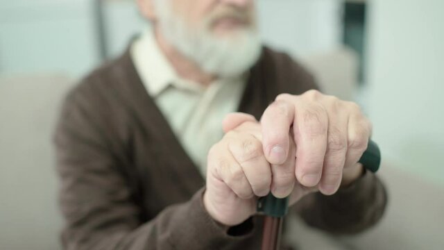 Elderly male hands on walking stick, weakness in old age, home care, health