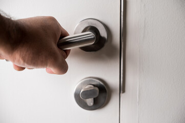 A man's hand was grasping the handle to open the door. He unlocked the door to enter the room.