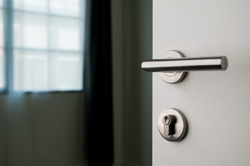 The white door has a steel handle and a keyhole. Turn into the living room of the house