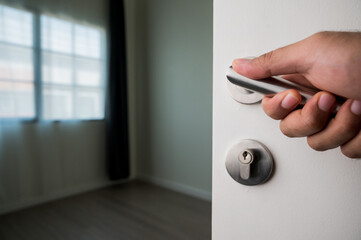 Naklejka premium A man's hand was grasping the handle to open the door. He unlocked the door to enter the room.