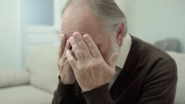 Depressed old man covering face with hands, incurable disease, negative thoughts