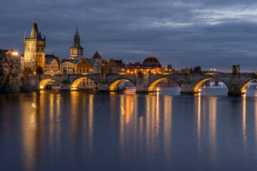 Obraz premium Charles Bridge on the Vltava River at sunset and colorful clouds and lights on the bridge in the early evening in the center of Prague
