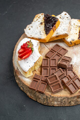 front view cake slices with chocolate bars on dark background biscuit fruit sweet