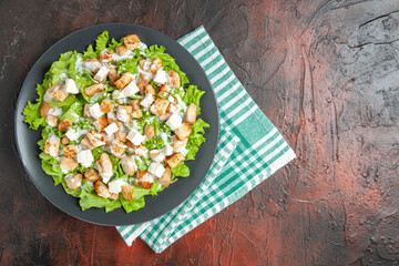 top view caesar salad on oval plate green white checkered napkin on dark red background with free place