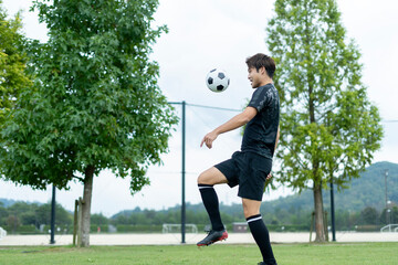 公園でサッカーをする若い男性