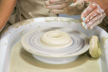 Women's hands and crafts on a potter's wheel in a pottery workshop