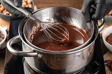 Confectioner stir in a bowl of melted chocolate. Production of confectionery or chocolate at home. Chocolate glaze.