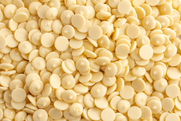 White chocolate chips or granules background, top view. Confectionery white chocolate.