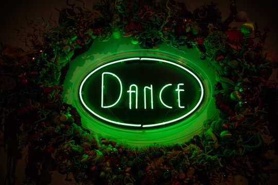 Green neon dance sign against dark background