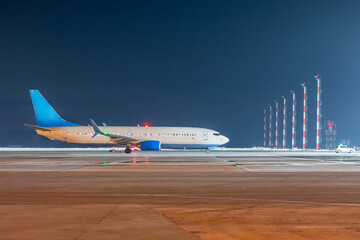 The passenger airliner moves behind the follow-me car at the night ariport apron