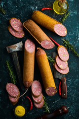 Delicious salami with rosemary and spices on a black background. Top view. Rustic style.